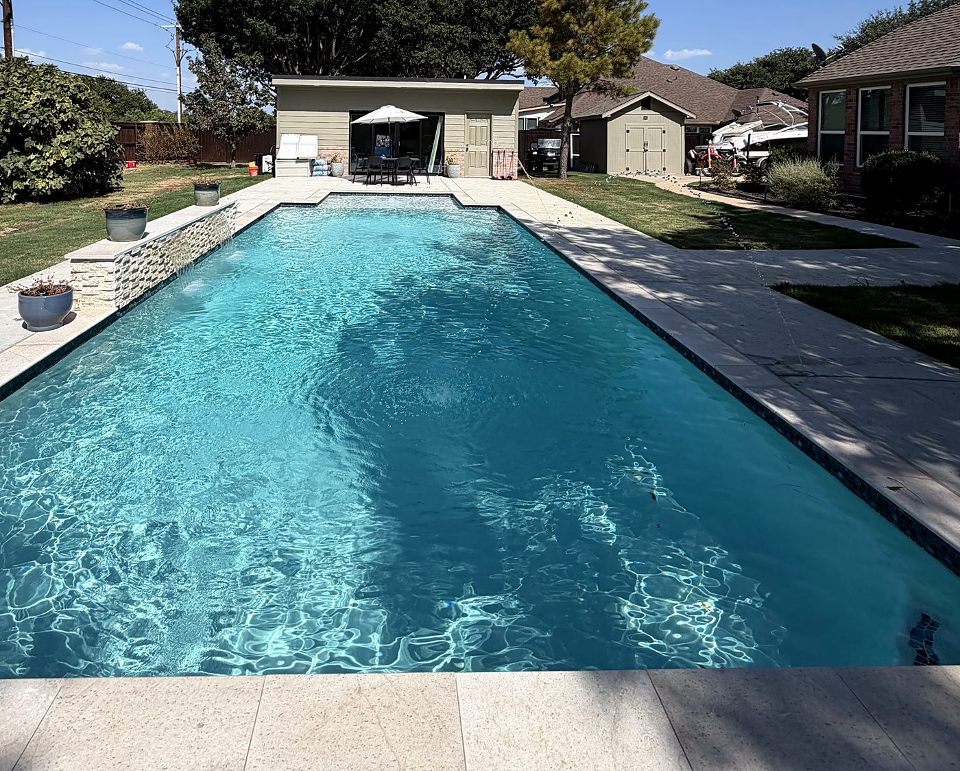 Long pool with stacked-stone water wall and planters