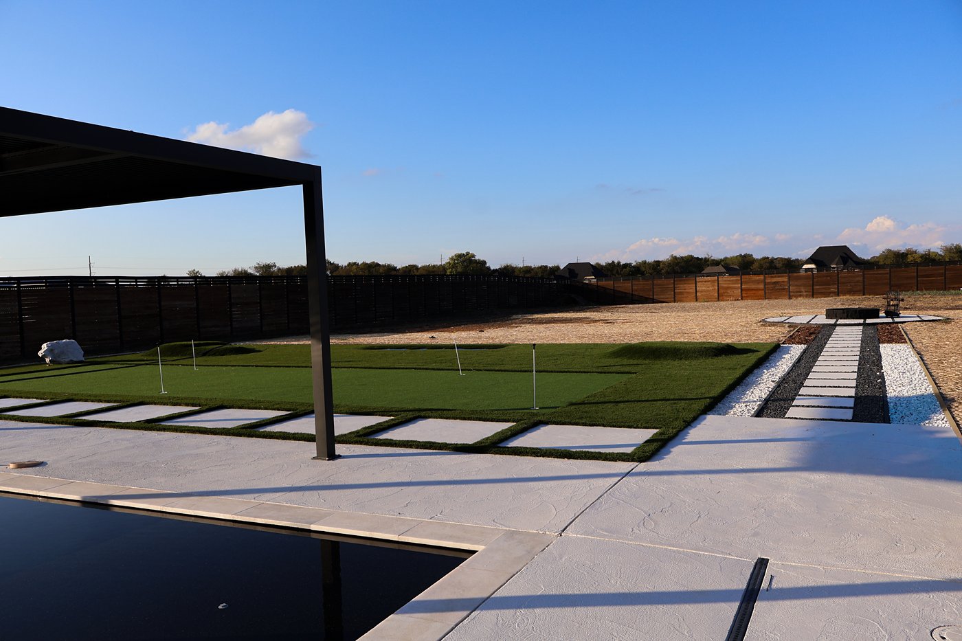 Putting green, paver walkway and pool deck at sunset