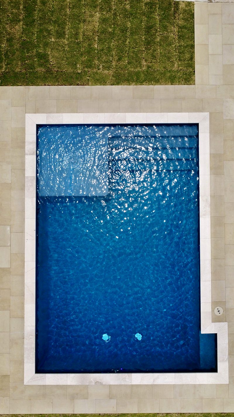 Overhead drone view of a pool with an interior bench and corner steps
